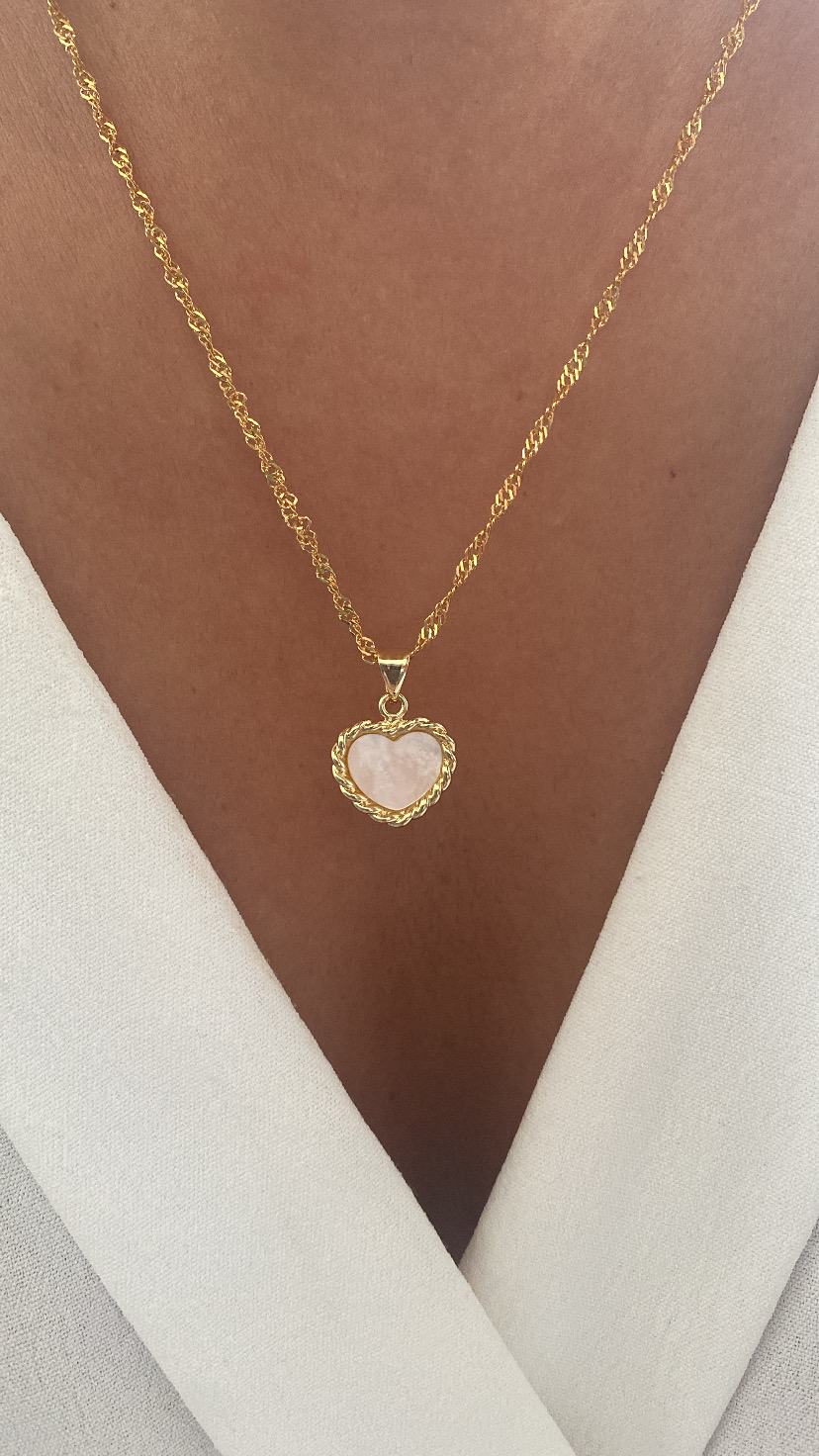 Colar dourado com pendente de coração com pedra rosa.