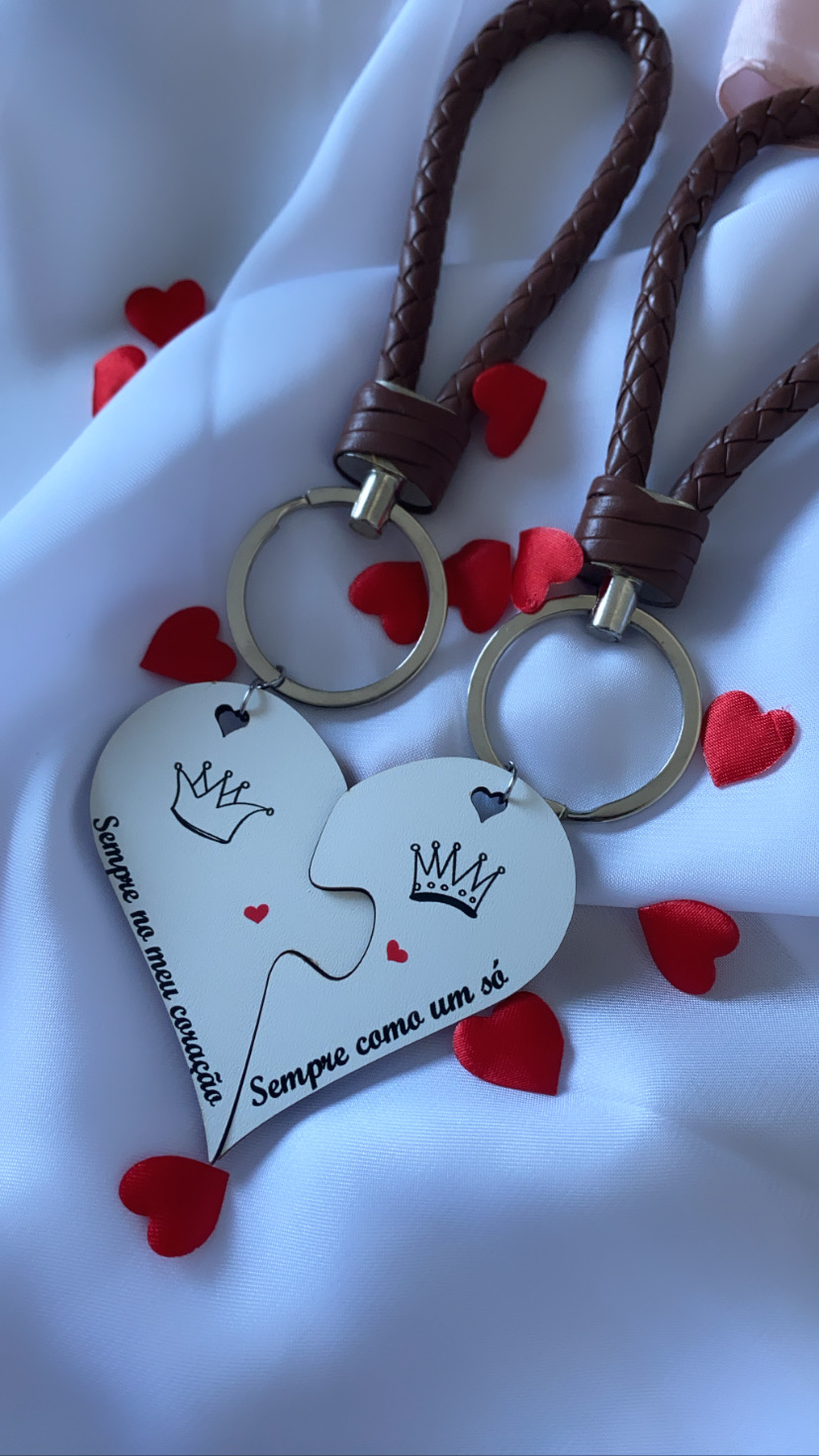Par de chaveiros couro com pingentes coração partido branco com texto em português e corações vermelhos no tecido de fundo