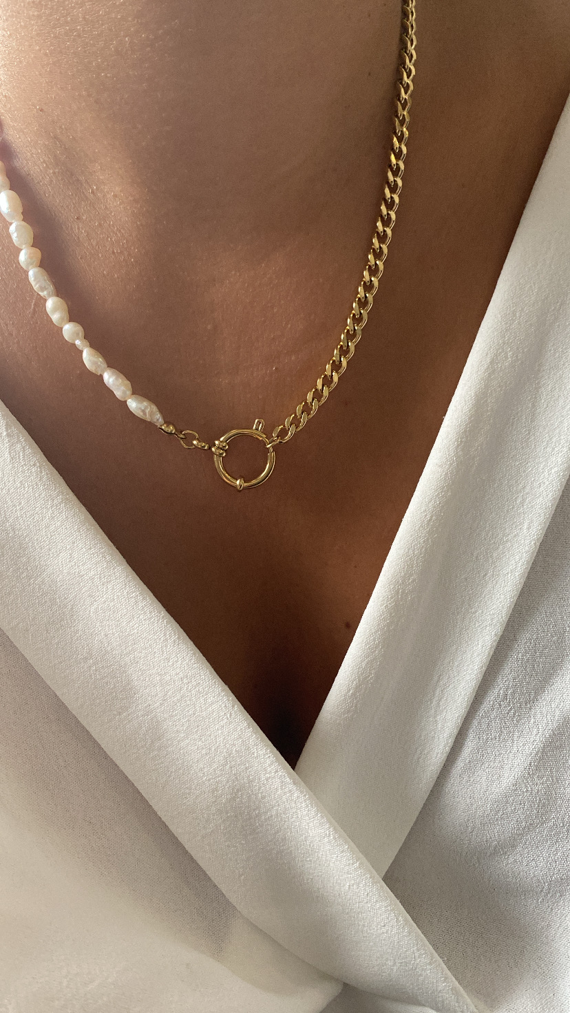Colar metade corrente dourada e metade pérolas brancas sobre decote branco.