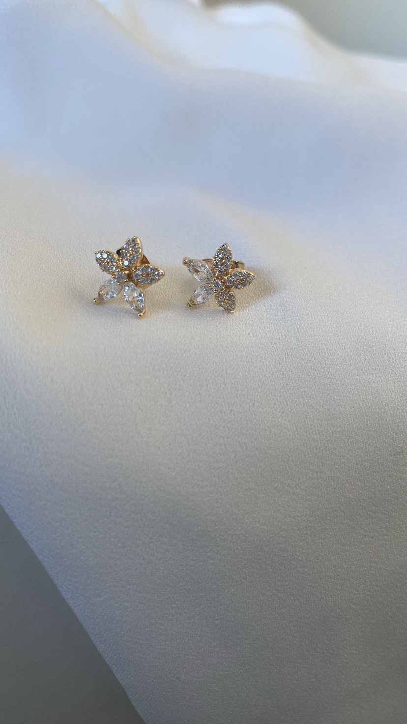 Brincos florais com pedras brilhantes sobre tecido branco