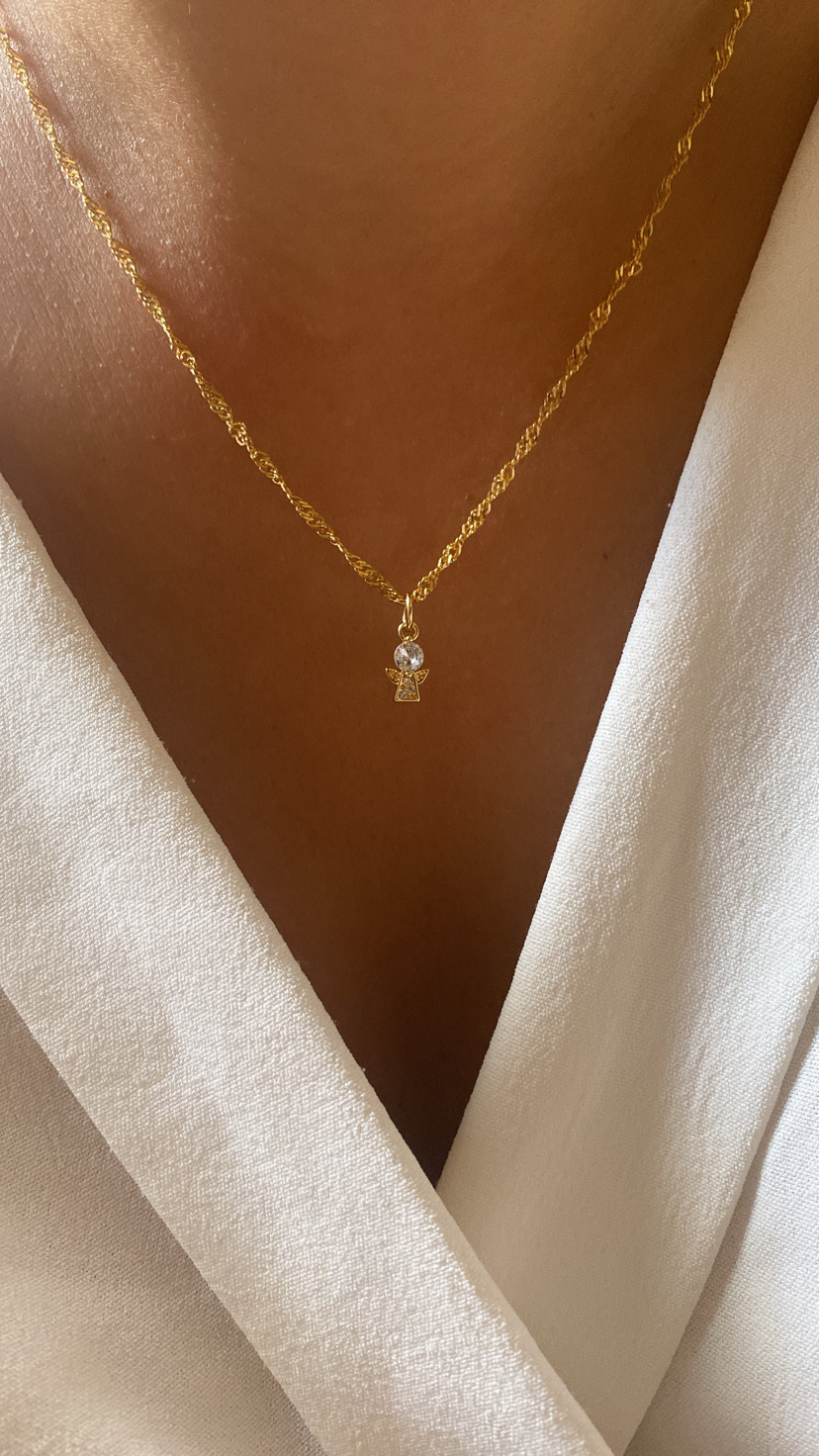 Colar dourado com pendente em forma de cruz e detalhe circular transparente