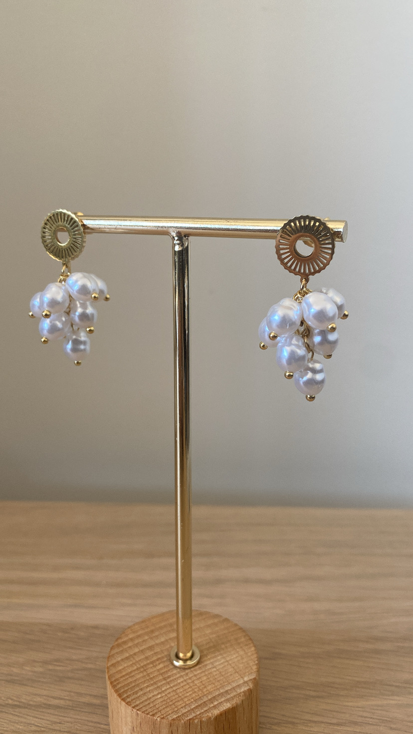 Brincos dourados com pérolas em suporte de madeira