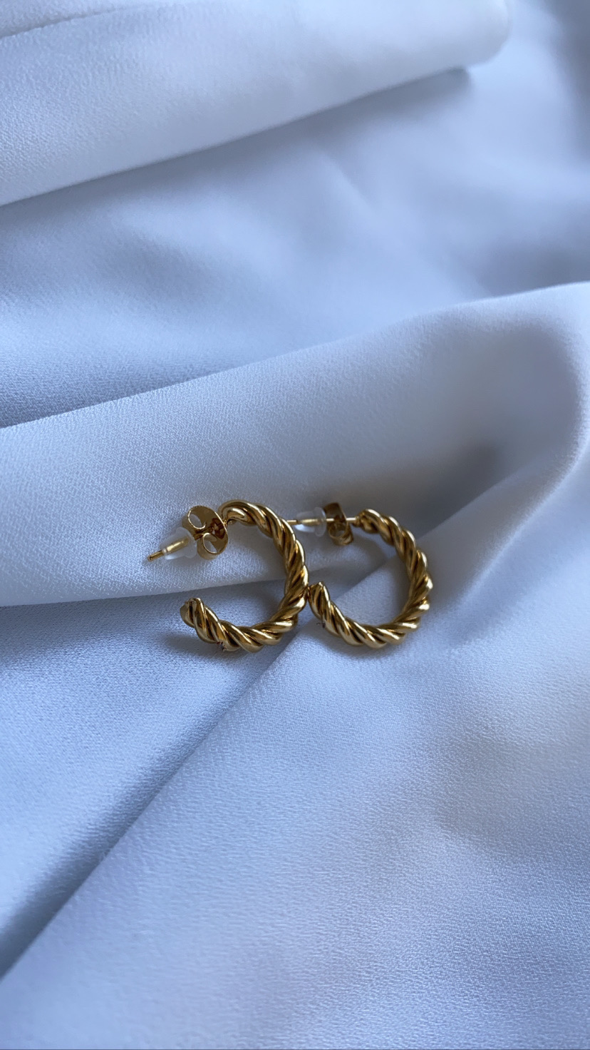 Brincos de argola dourados com textura torcida sobre tecido branco