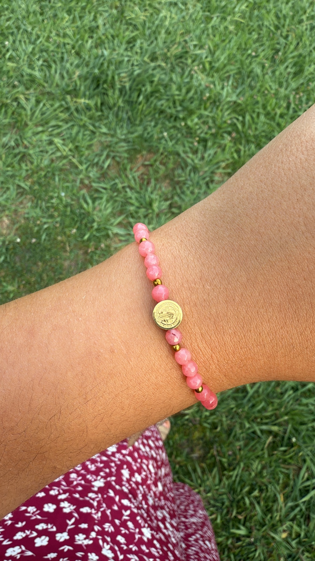 Pulseira rosa e dourada com moeda central no pulso