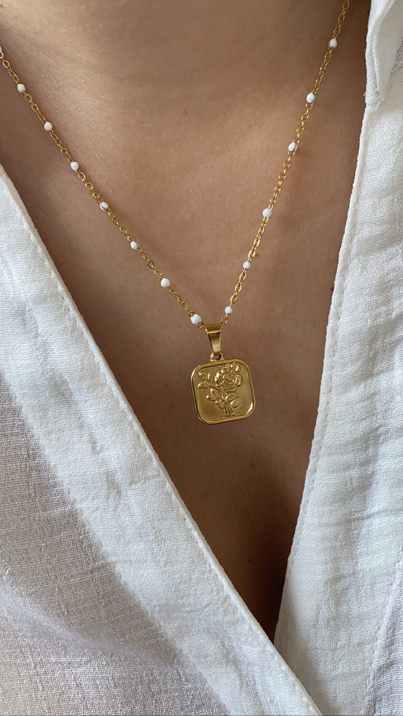 Colar dourado com contas brancas e pendente quadrado com relevo floral