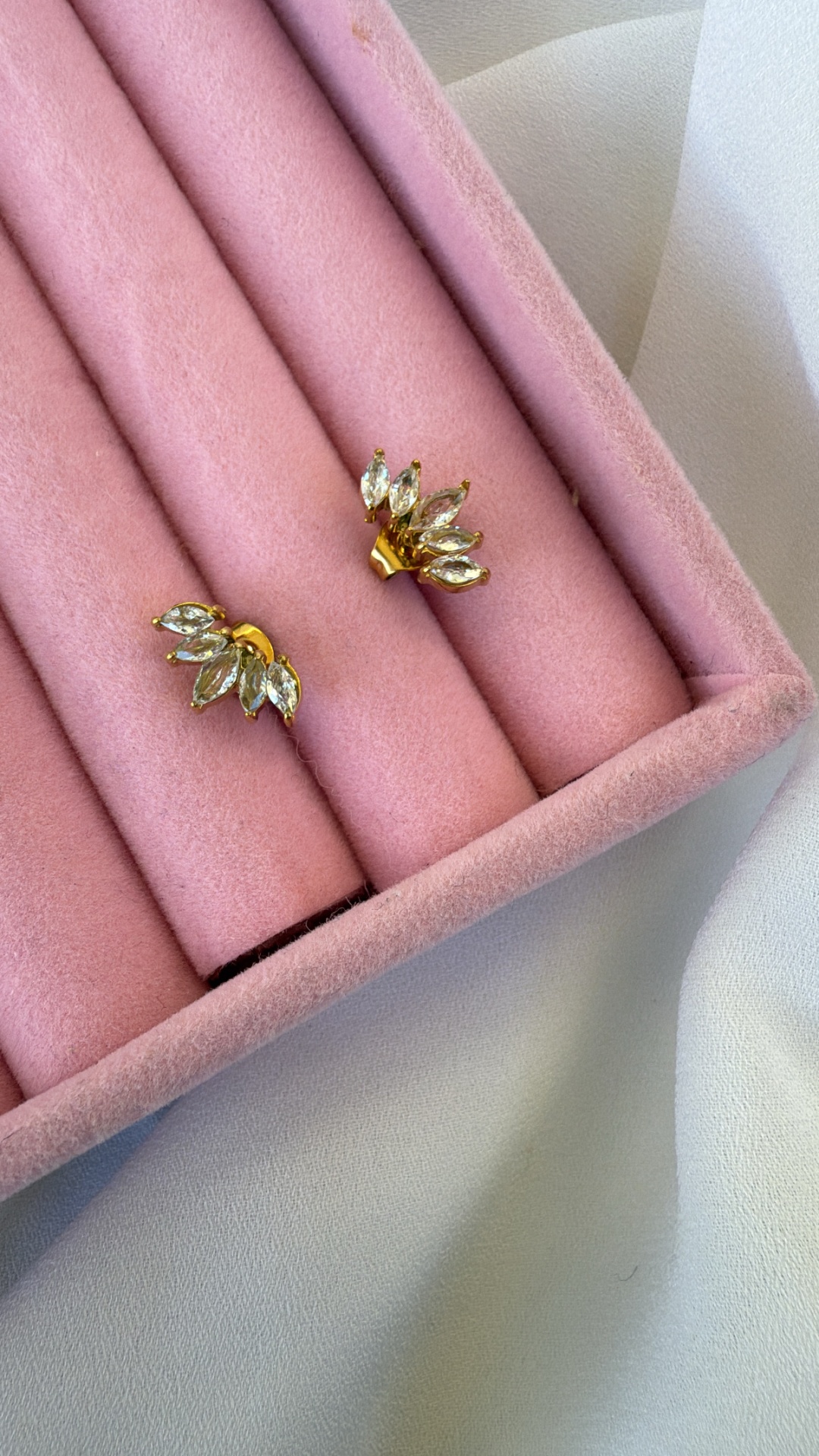 Brincos dourados com pedras transparentes em caixa de veludo rosa