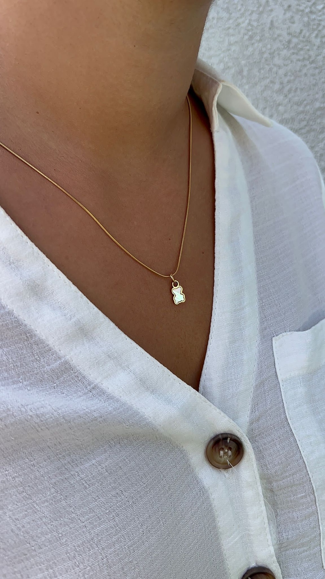 Colar dourado com pendente em silhueta e camisa branca com botões