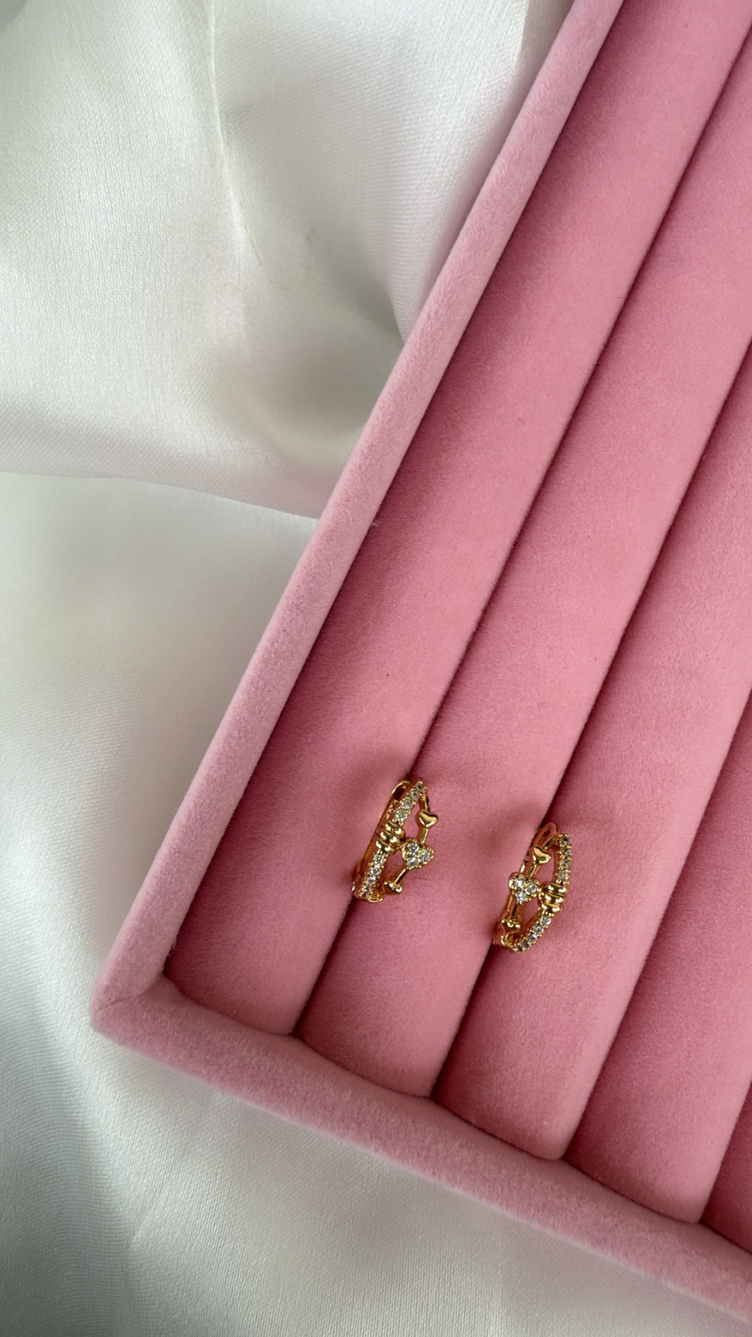 Brincos dourados com pedras em caixa rosa e tecido branco