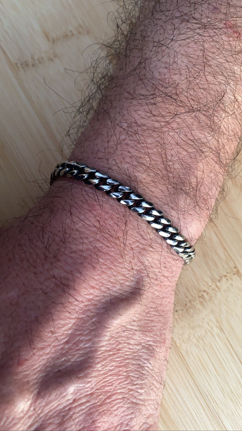 Pulseira de metal prateado com elos grossos entrelaçados no pulso