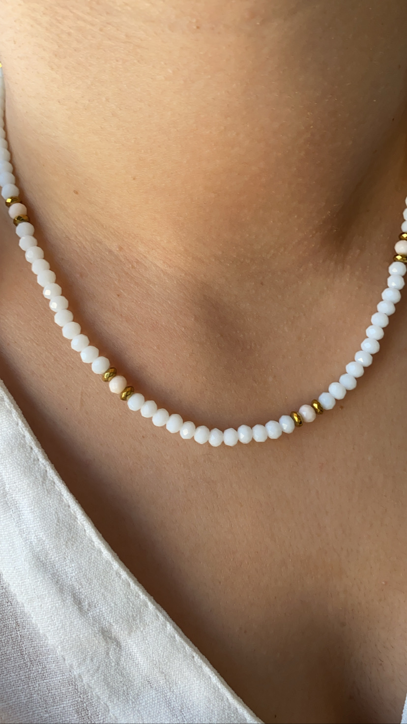 Colar de contas brancas e douradas ao redor do pescoço