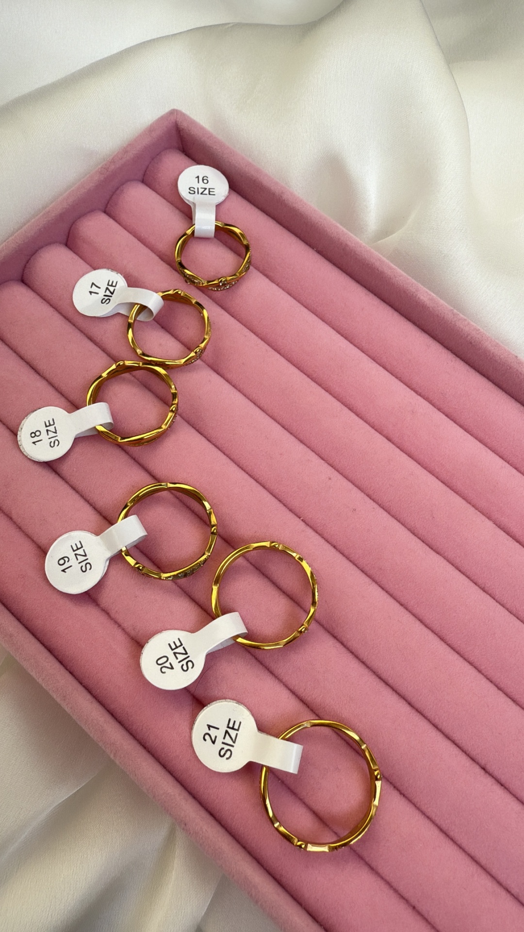 Conjunto de seis anéis dourados em caixa rosa com etiquetas de tamanho