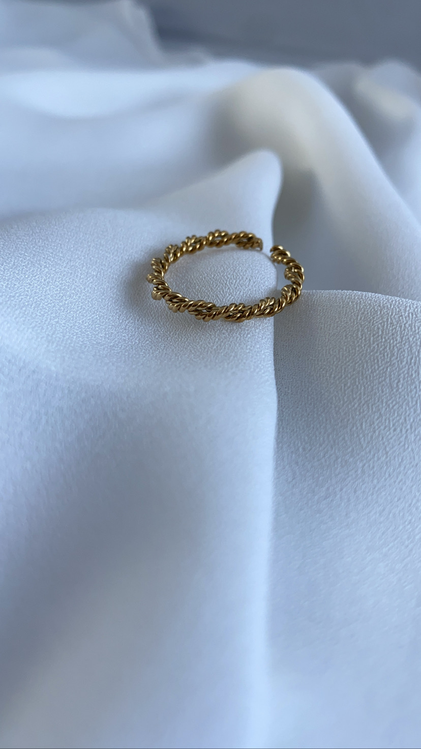 Anel dourado torcido sobre tecido branco