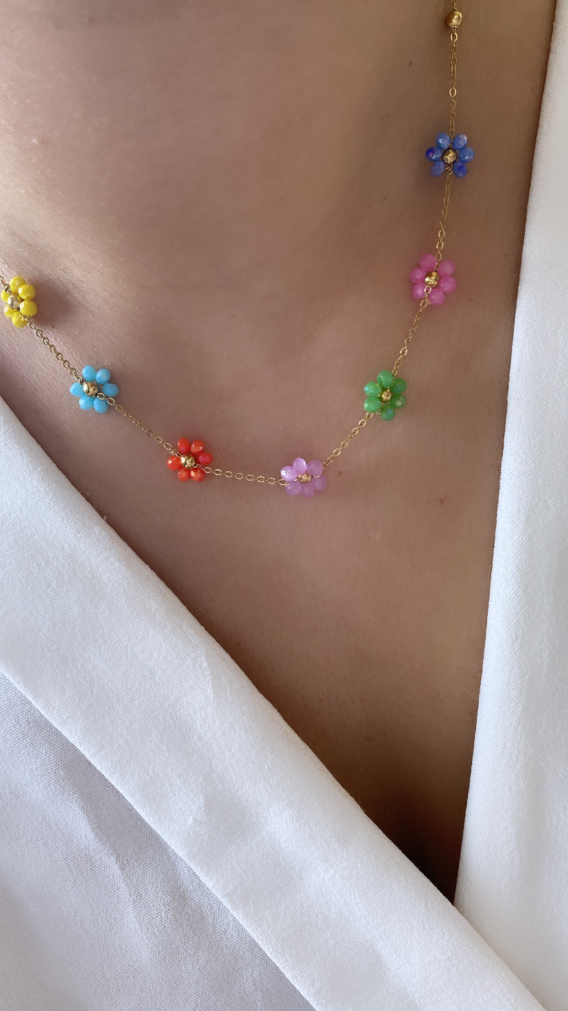 Colar com pequenas flores coloridas e corrente dourada sobre roupa branca