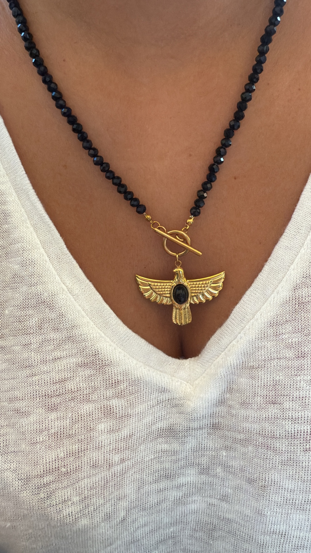 Colar com contas pretas e pendente dourado em forma de águia com pedra preta