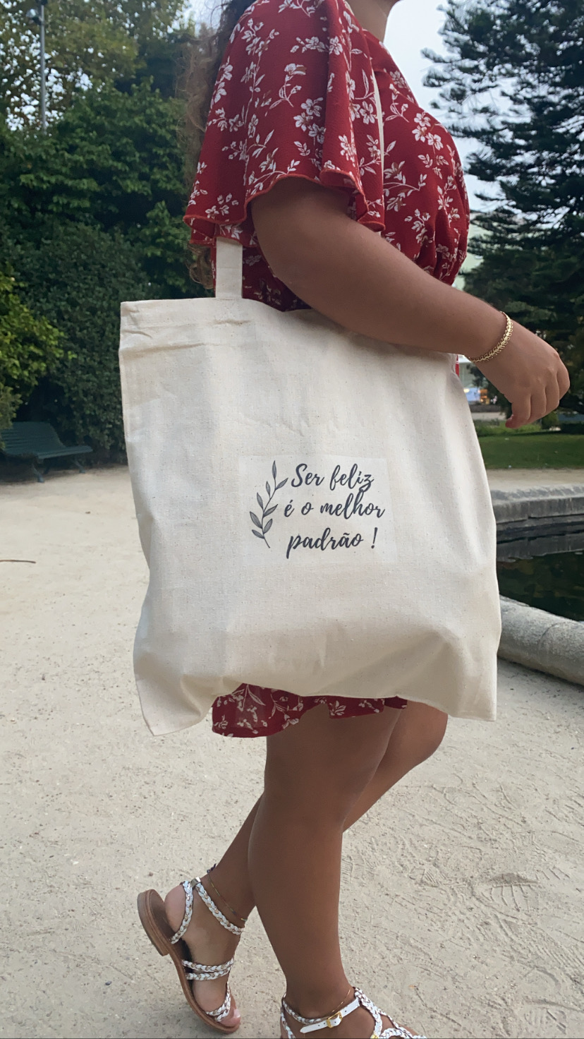 Mala tote de tecido com texto em português e pessoa com vestido vermelho