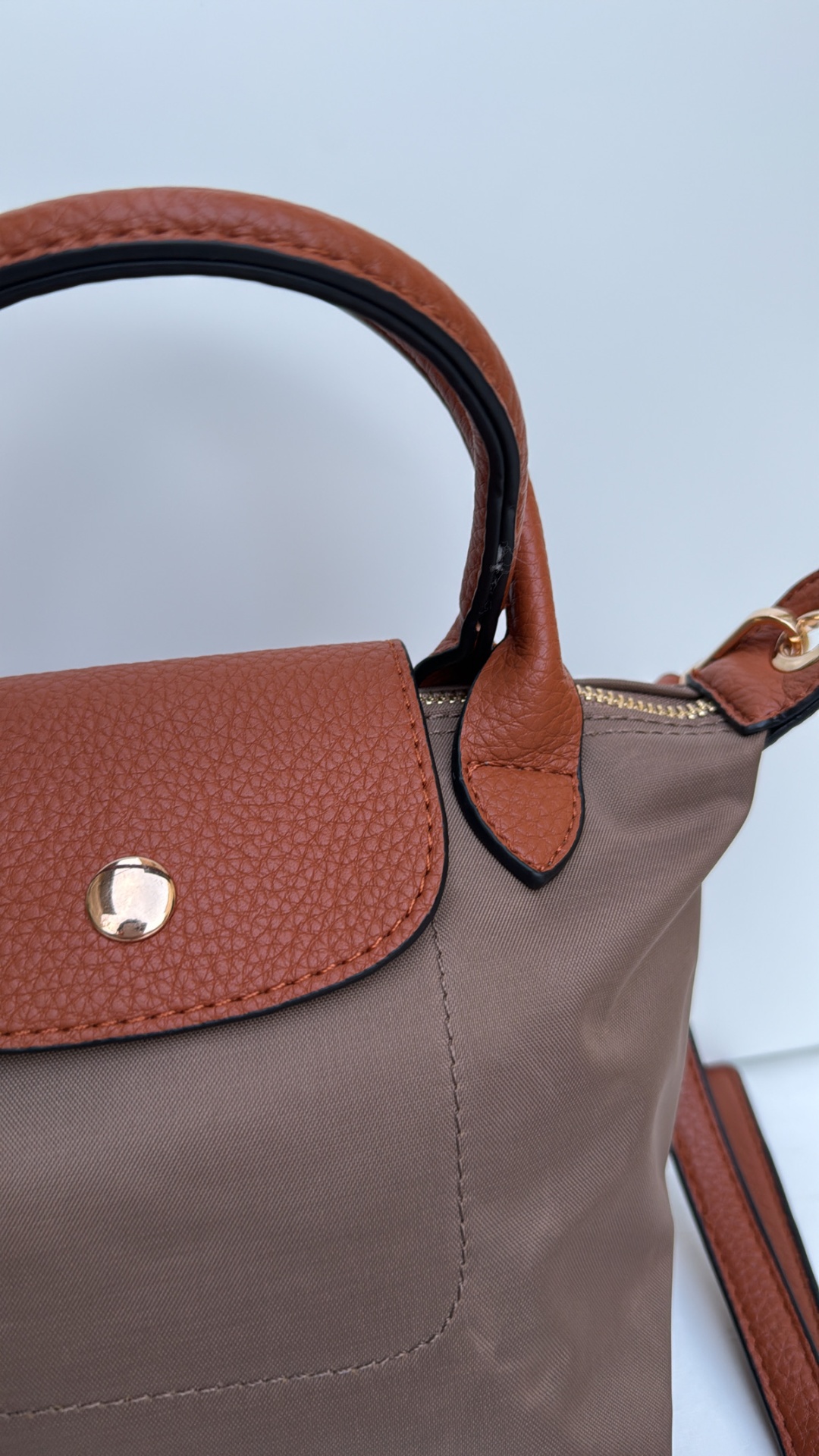 Mala de mão em tecido castanho com detalhes em pele castanha e fecho dourado