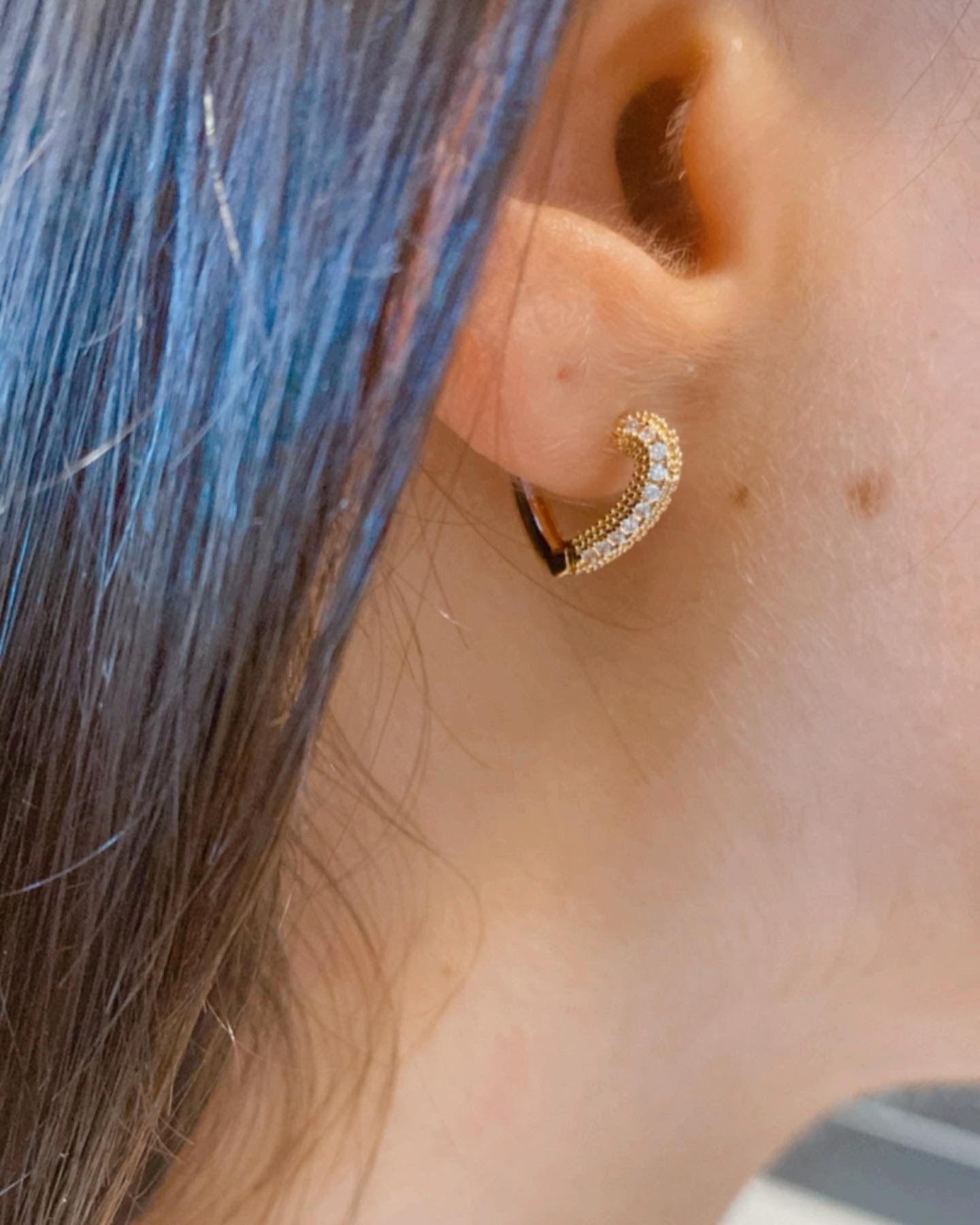 Brinco meia-lua com pedras brilhantes na orelha de uma pessoa