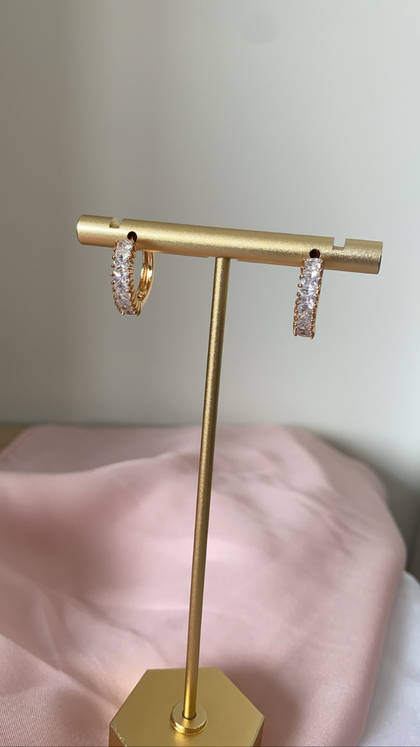 Brincos de argola dourados com pedras numa base dourada hexagonal