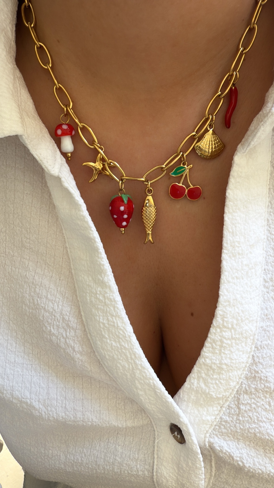 Colar dourado com pendentes coloridos em formas variadas usado com camisa branca