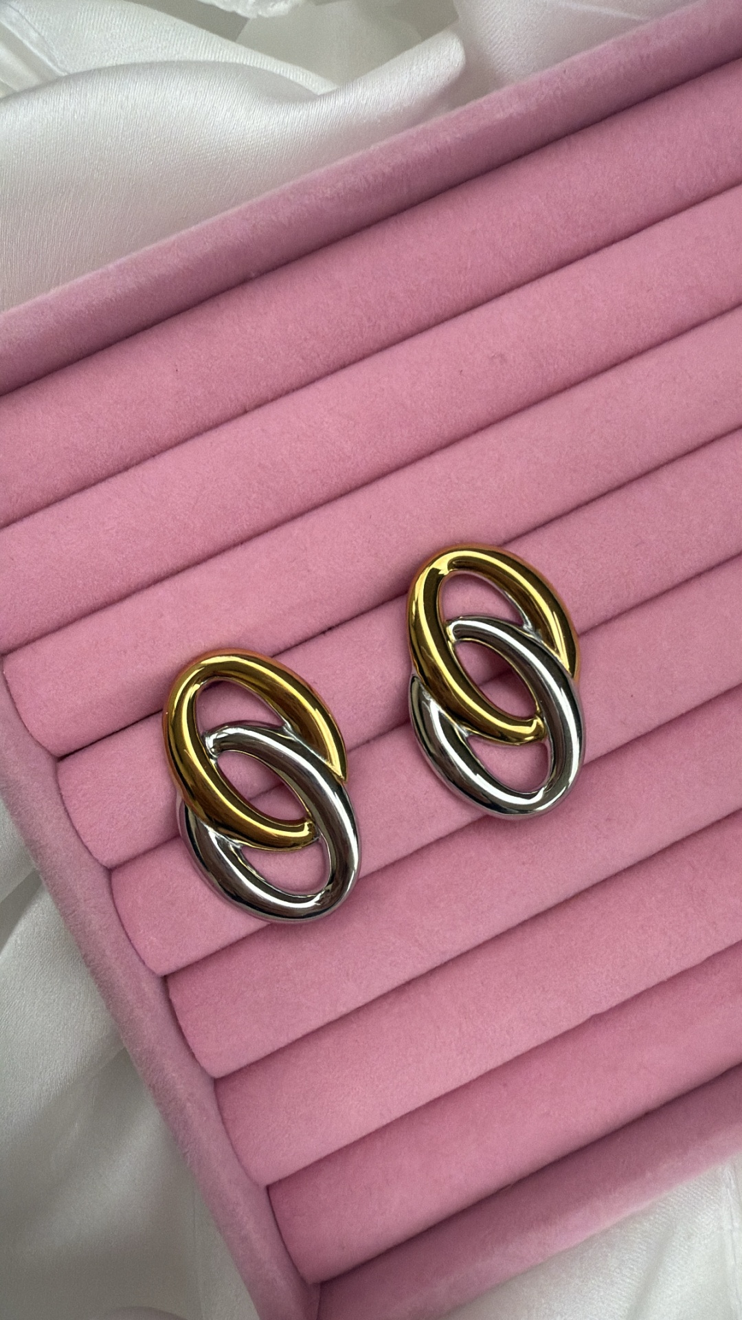 Brincos de metal dourado e prateado em caixa rosa acolchoada
