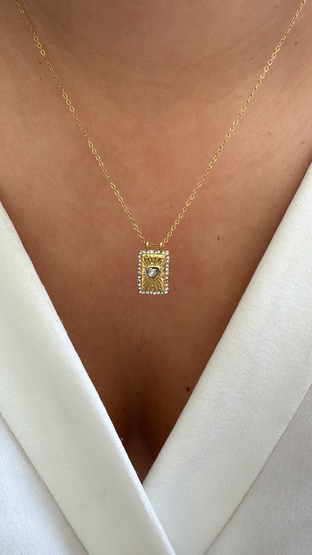 Colar dourado com pendente retangular e pedra em forma de coração