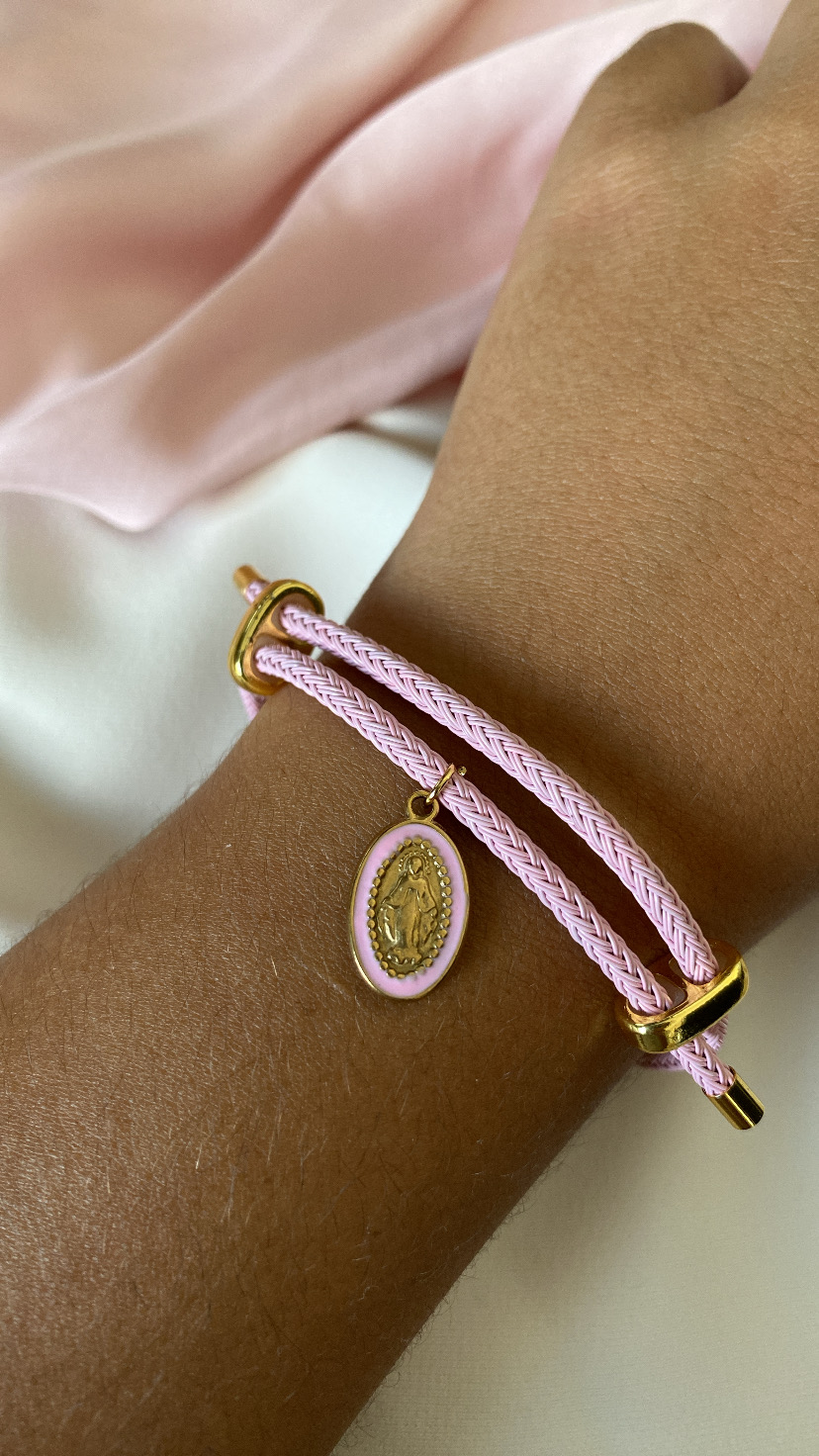 Pulseira rosa com pendente dourado em pulso