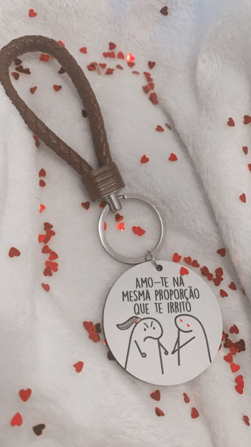 Porta-chaves com alça castanha, pendente redondo branco com texto e desenho, sobre fundo branco com confetis em forma de corações vermelhos