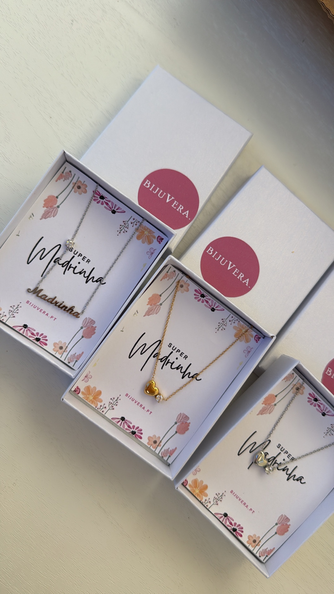 Três caixas com colares de coração e etiquetas BIJUVERA