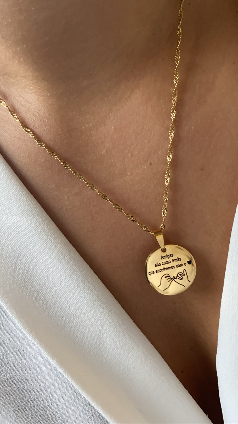 Colar dourado com pendente gravado usado no pescoço