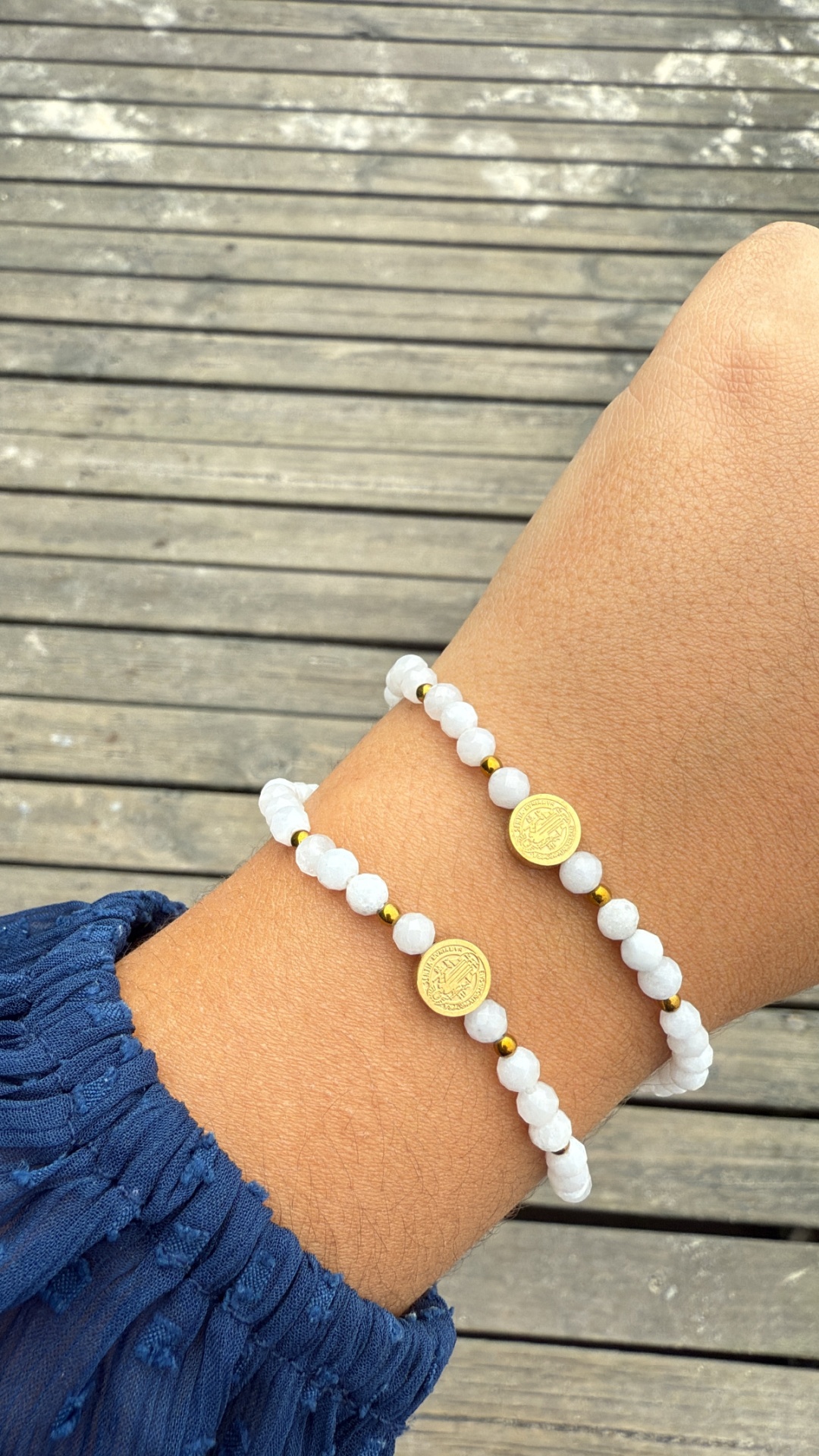 Pulseiras de contas brancas com moedas douradas no pulso