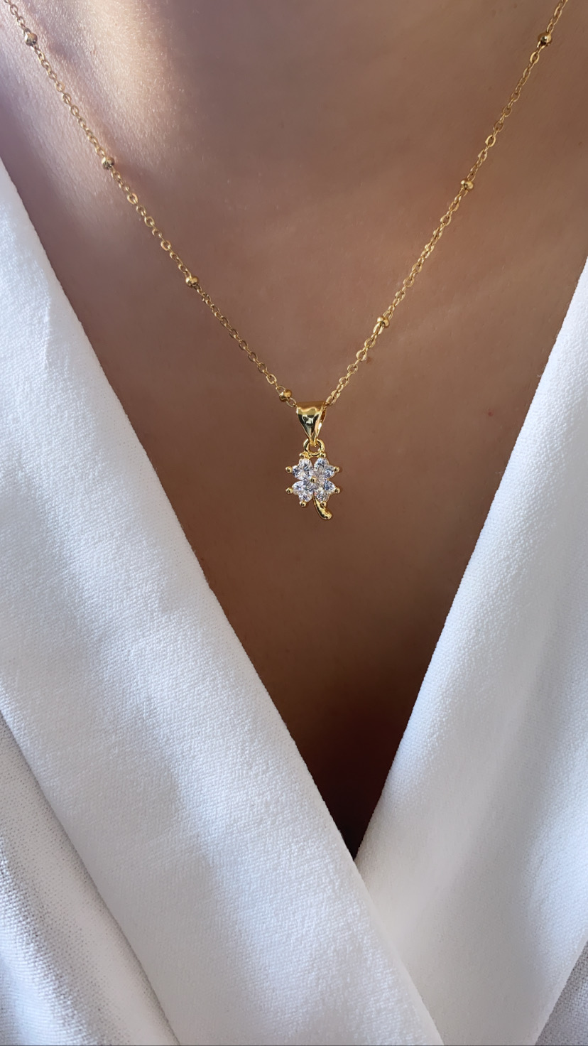 Colar dourado com pendente de folha e pedras translúcidas