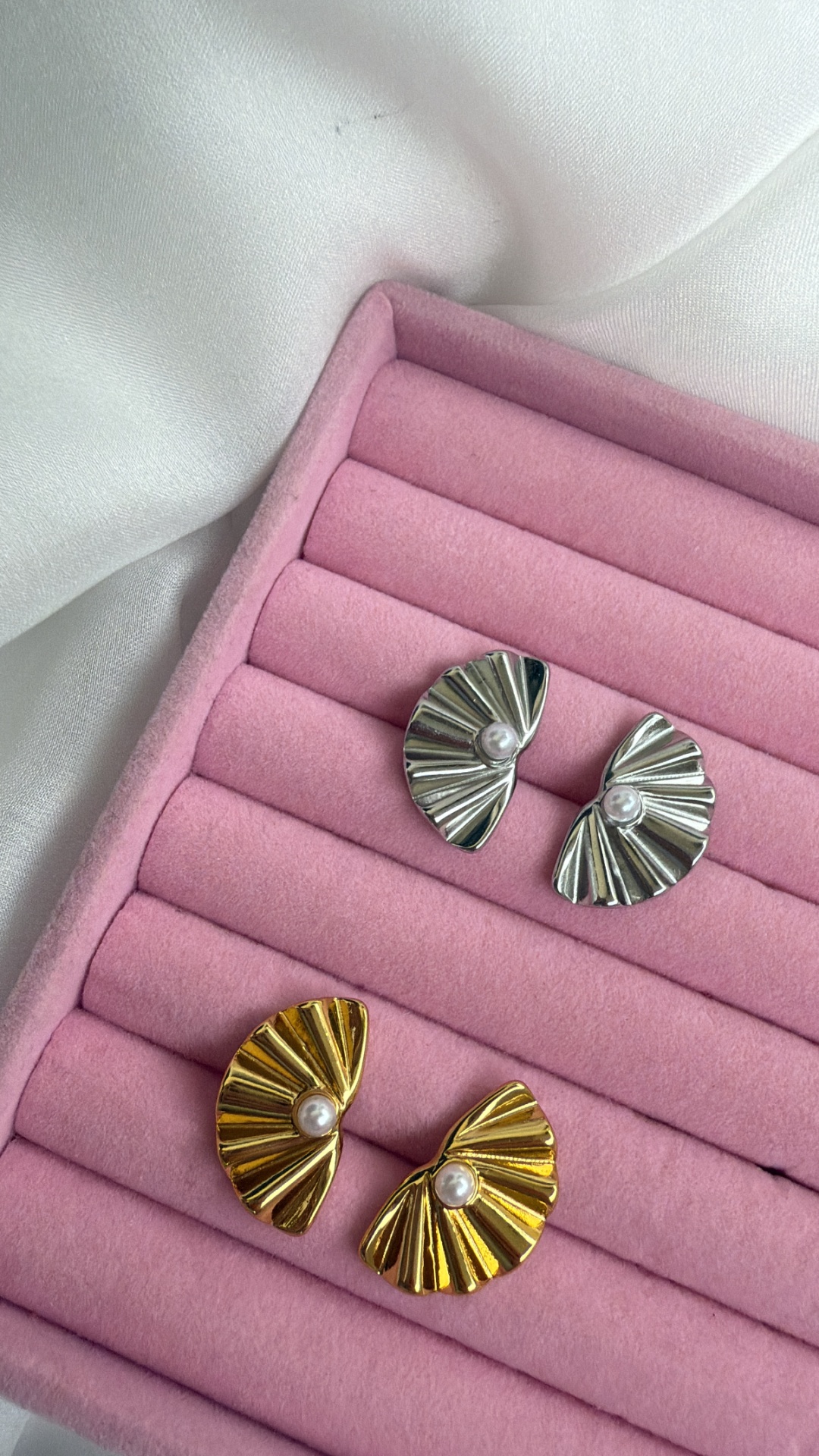 Dois pares de brincos em metal prateado e dourado com pérola, numa caixa rosa de veludo