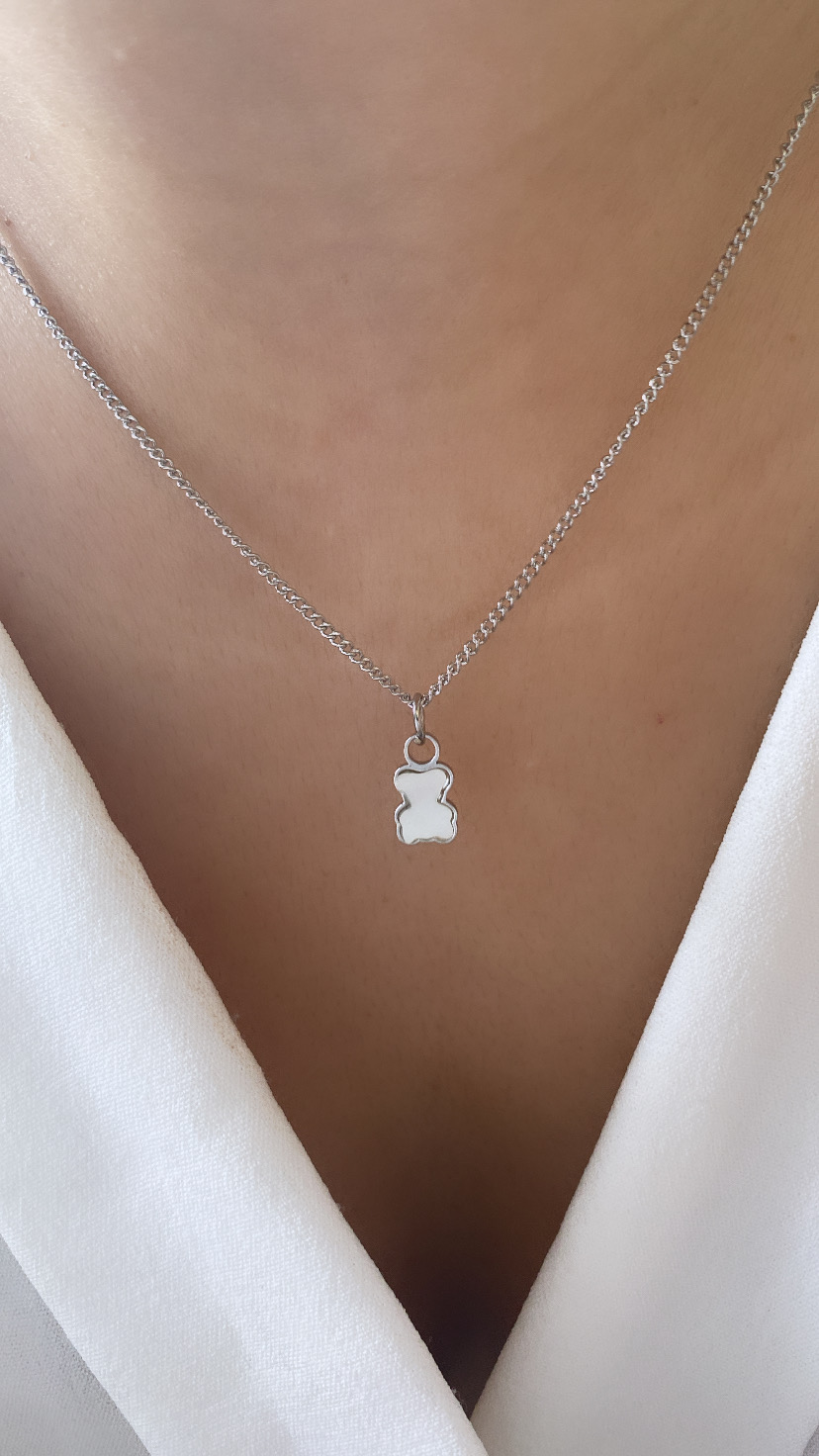 Colar de corrente prateada com pendente de ursinho prateado ao pescoço