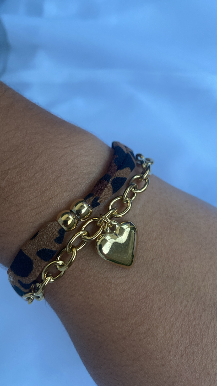 Pulseira dupla dourada com pendente de coração e fita animal print no pulso