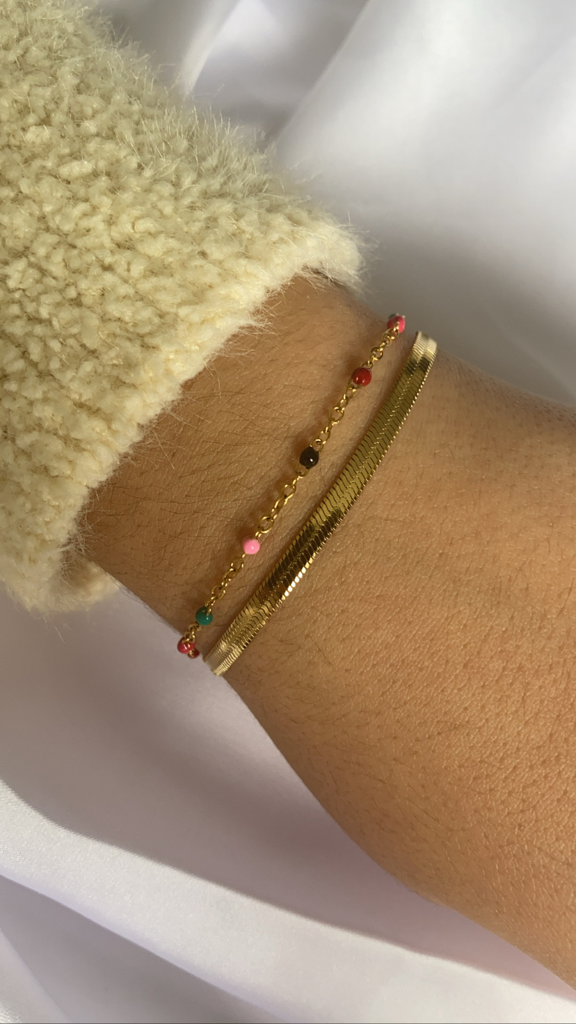 Pulso com duas pulseiras douradas e suéter de malha bege