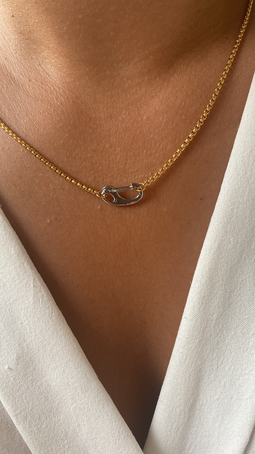 Colar dourado com fecho prateado em mola no pescoço