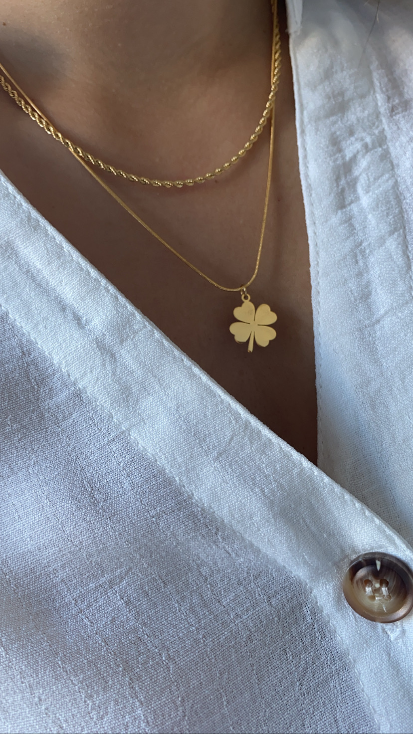 Colar duplo dourado com pendente de trevo em blusa branca