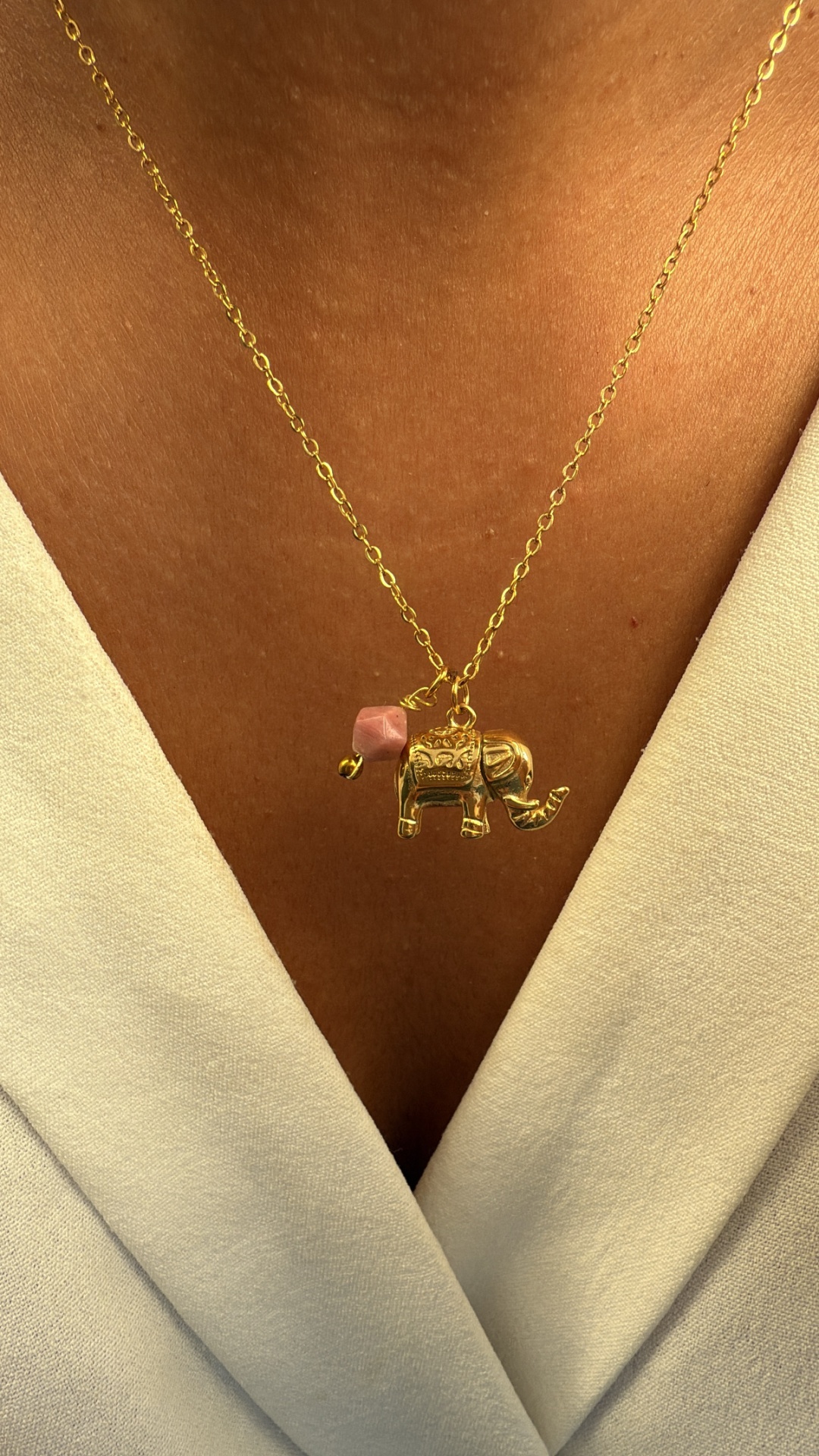 Colar dourado com pendente de elefante e pedra rosa