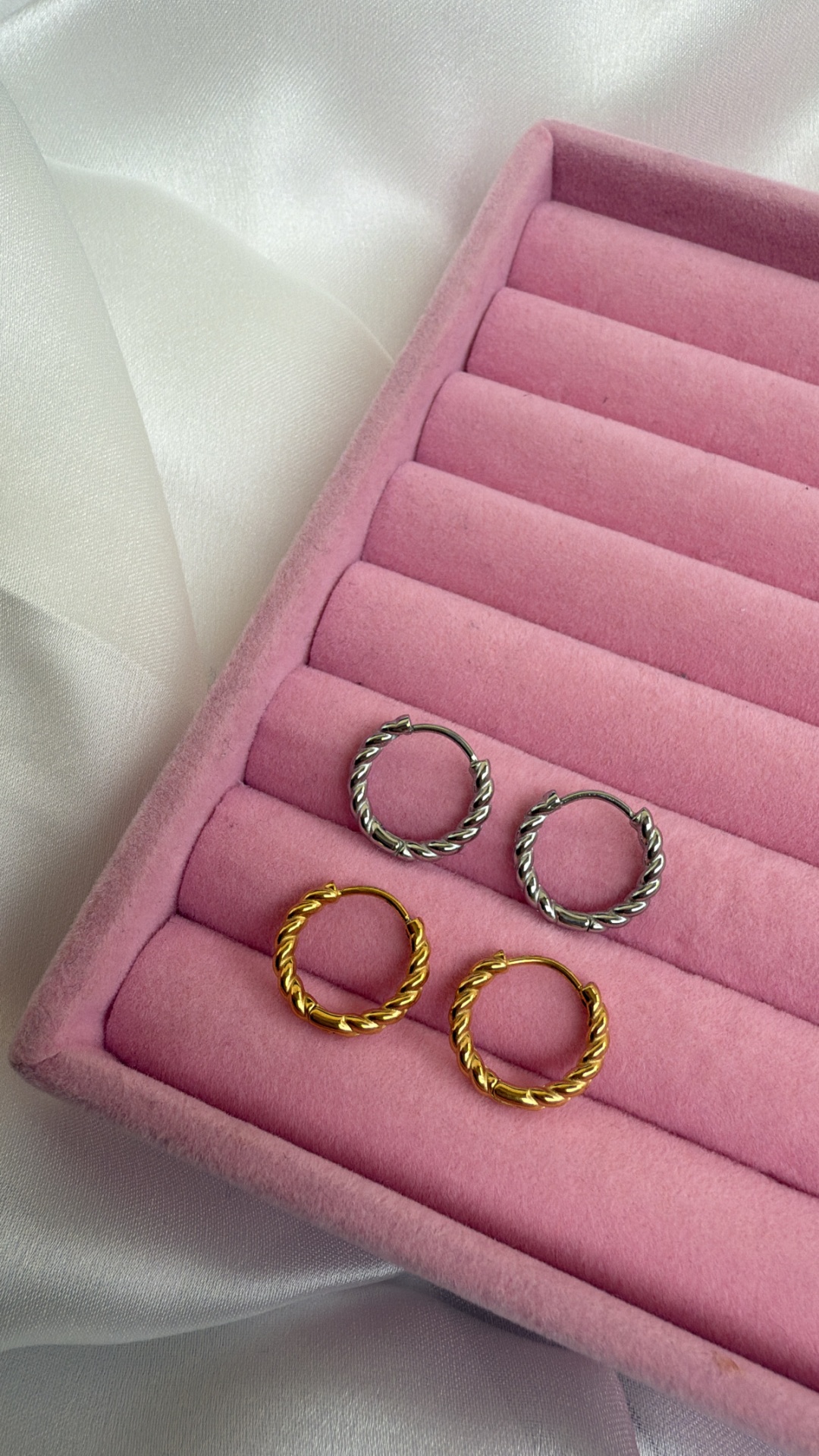 Par de brincos de argola dourados e prateados em caixa de veludo rosa