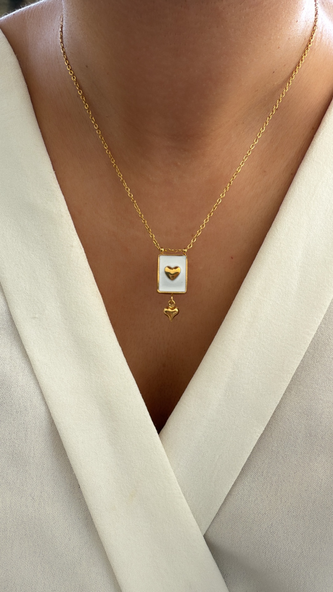 Colar dourado com pendentes de corações sobre roupa branca