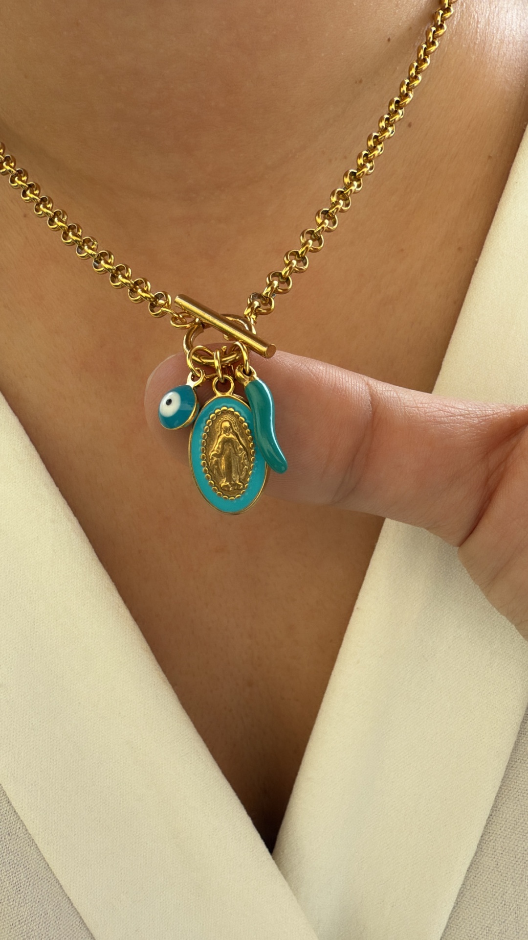Colar dourado com pendentes azul e dourado usado em pessoa com roupa bege