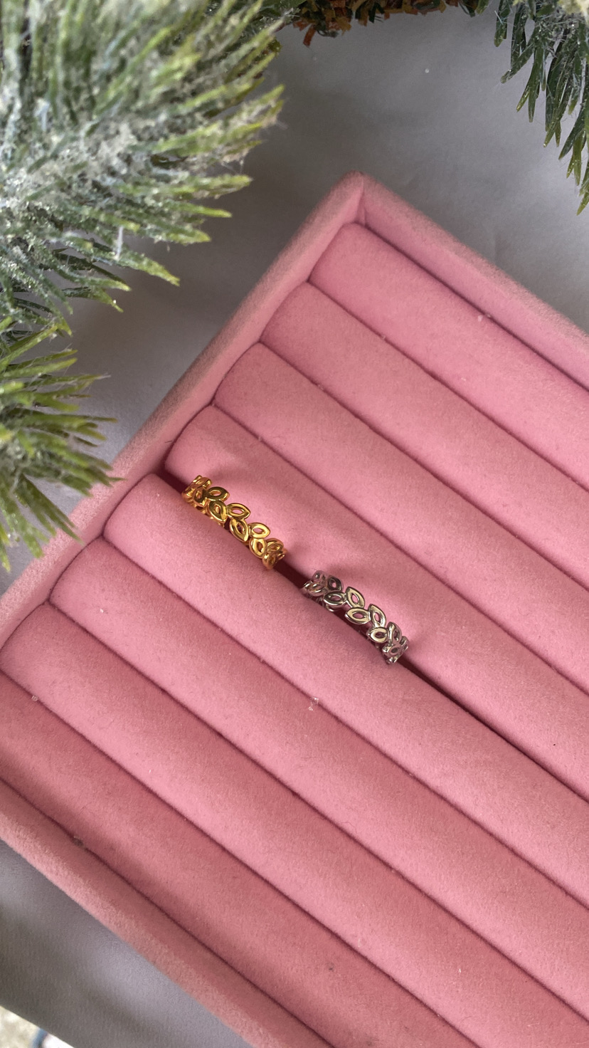 Dois anéis de folhas, dourado e prateado, numa caixa de joias rosa.