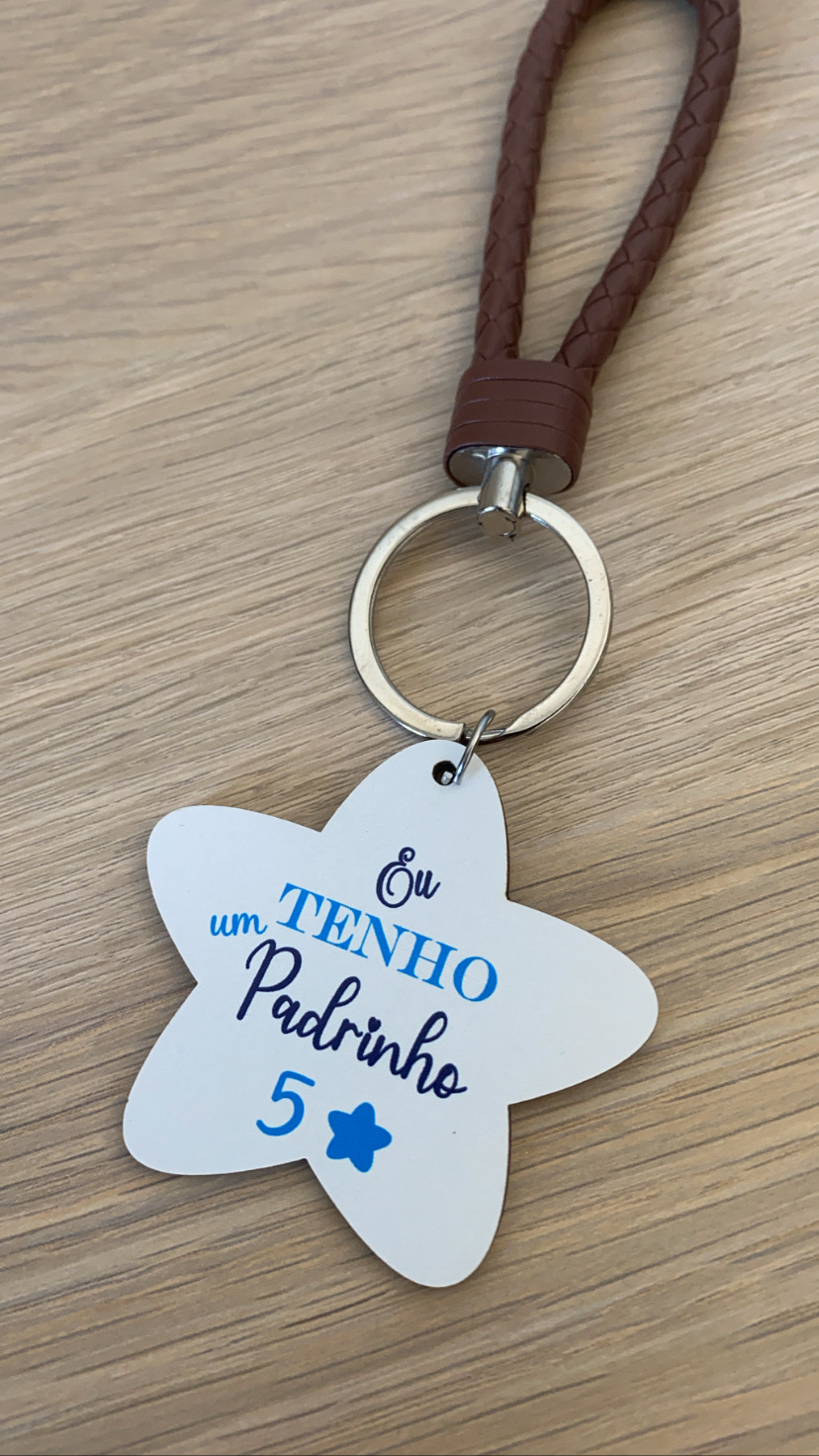Chaveiro estrela branca com texto em azul e preto e cordão castanho trançado