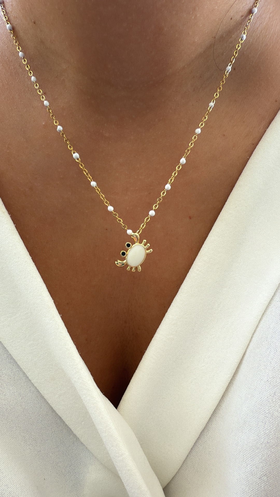 Colar dourado com pérolas e pendente caranguejo branco