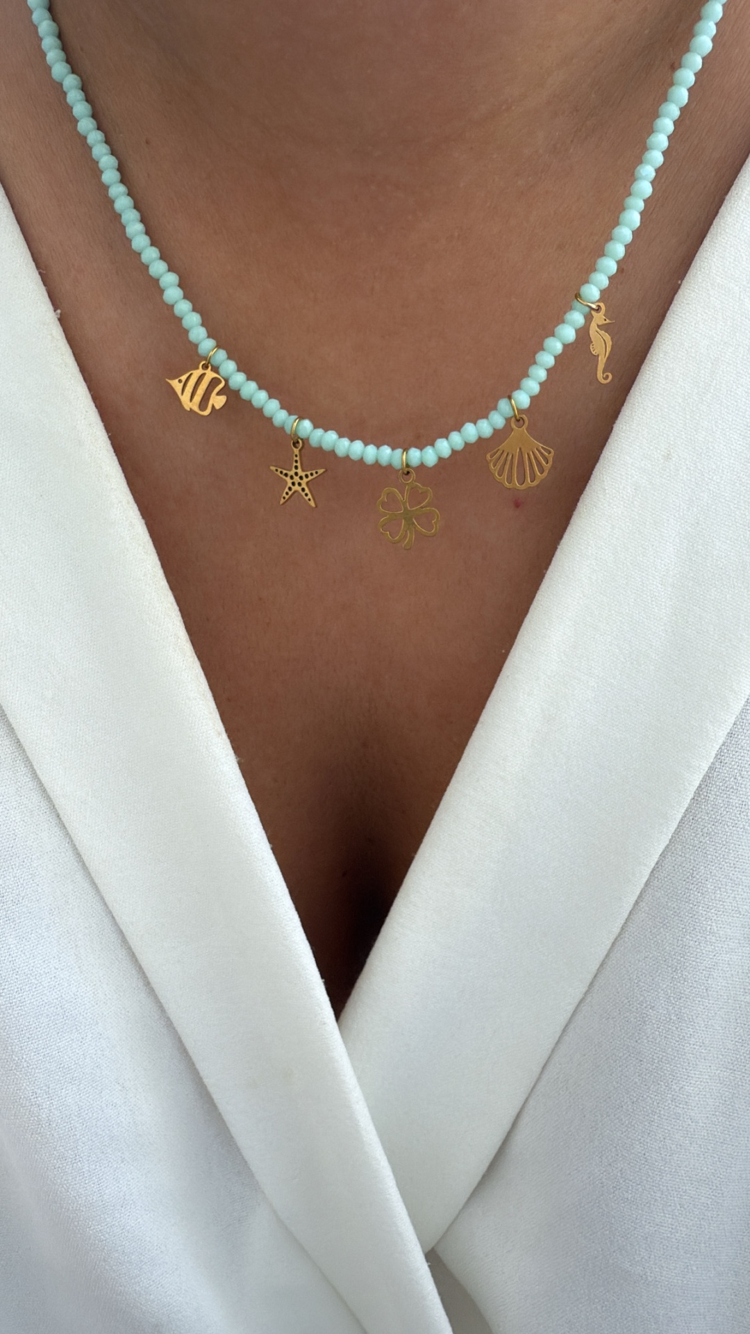 Colar com contas azuis e pendentes dourados em forma de animais marinhos e trevo