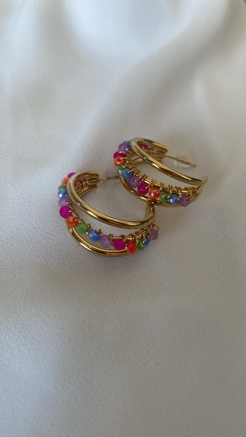 Brincos argola dourados com contas coloridas sobre tecido branco