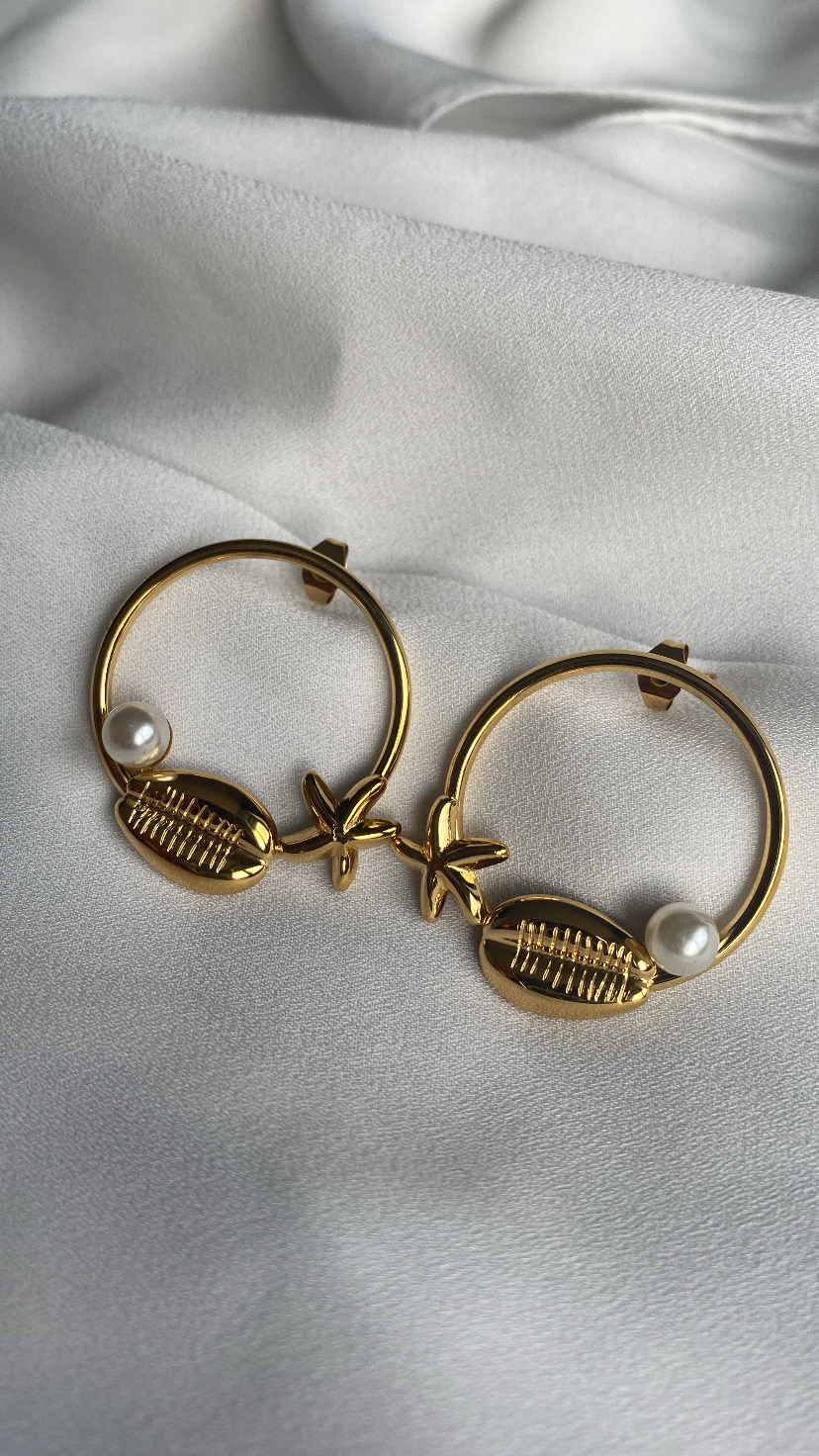 Par de brincos dourados com concha e pérola em fundo branco