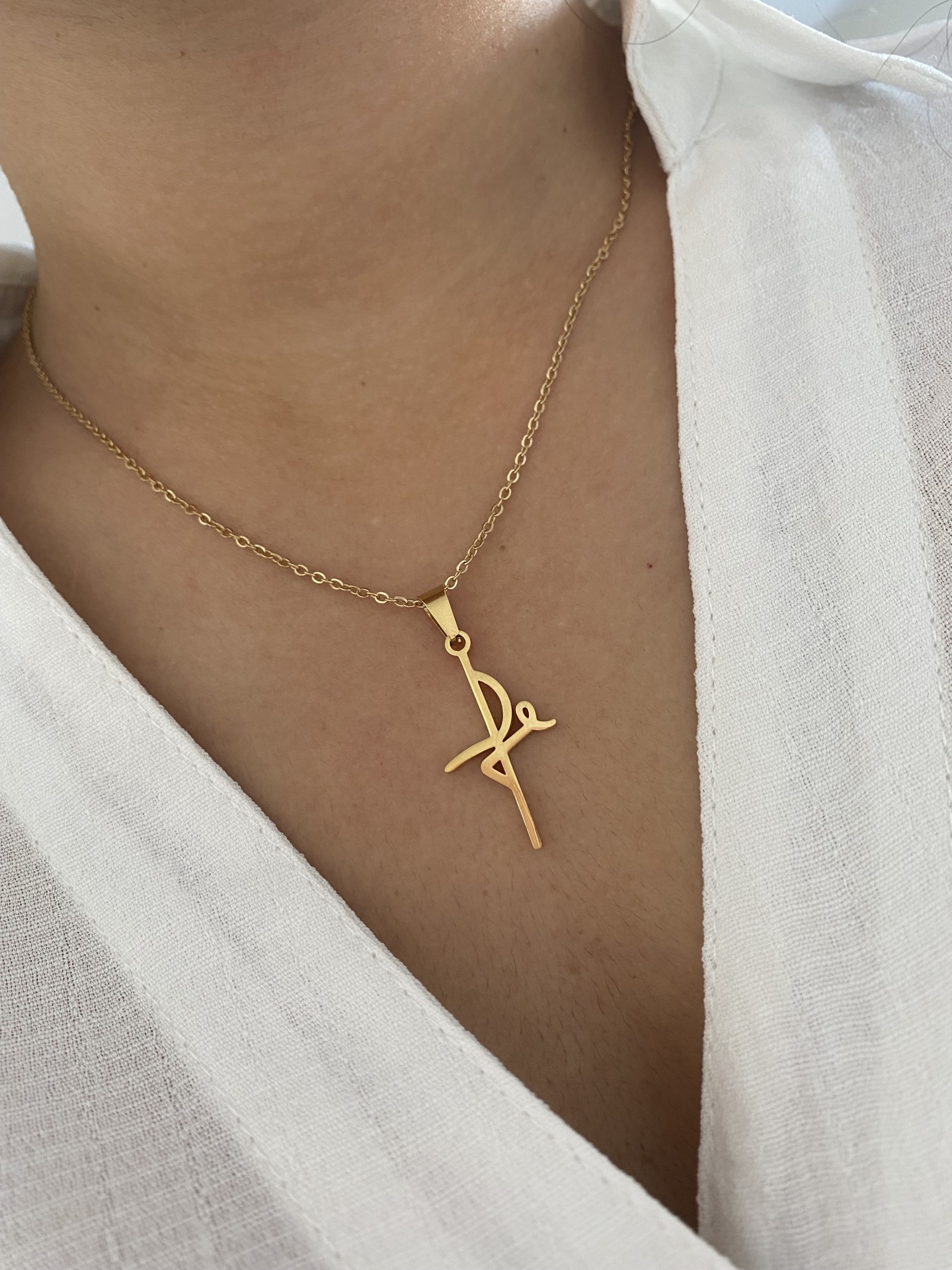 Colar dourado com pendente estilizado usado no pescoço