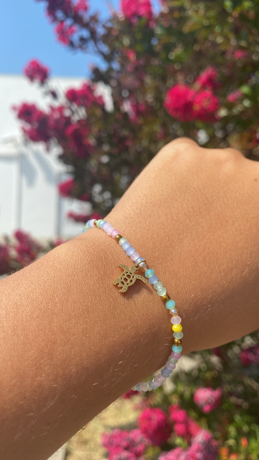 Pulseira colorida com pendente dourado em forma de abacaxi no pulso