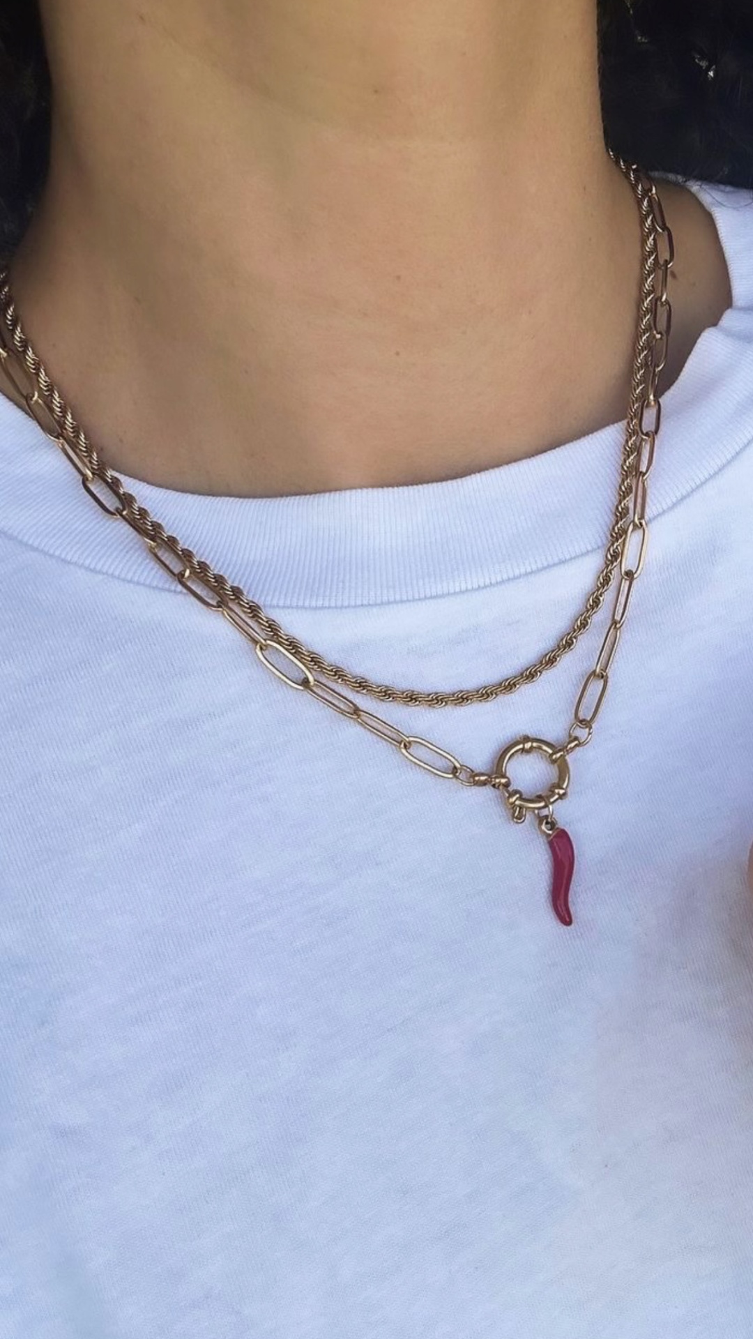 Colar duplo dourado com pendente vermelho em pimenta sobre t-shirt branca
